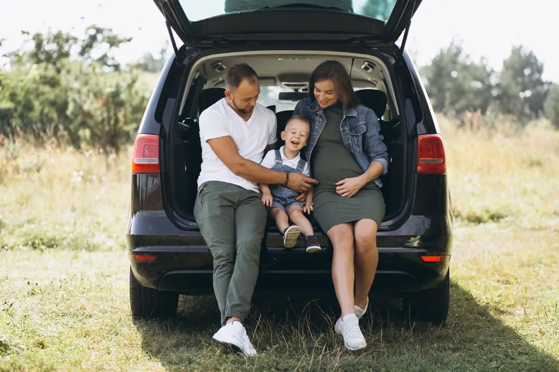 Familia sentada en el baúl abierto de su auto